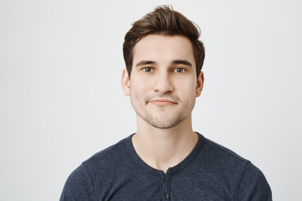 Portrait of a smiling young man against a grey background